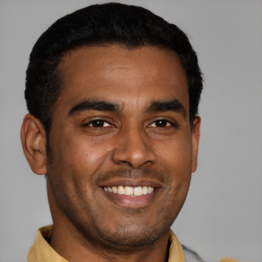 Joyful black young-adult male with short  brown hair and brown eyes