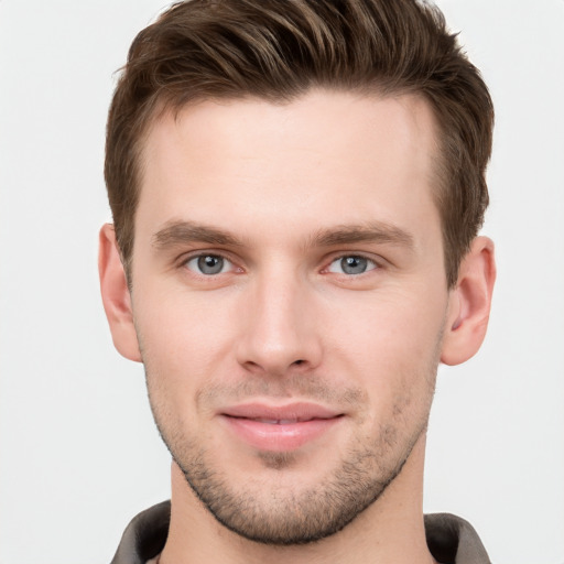 Joyful white young-adult male with short  brown hair and grey eyes