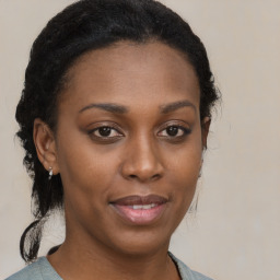 Joyful black young-adult female with long  brown hair and brown eyes