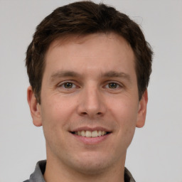 Joyful white young-adult male with short  brown hair and grey eyes