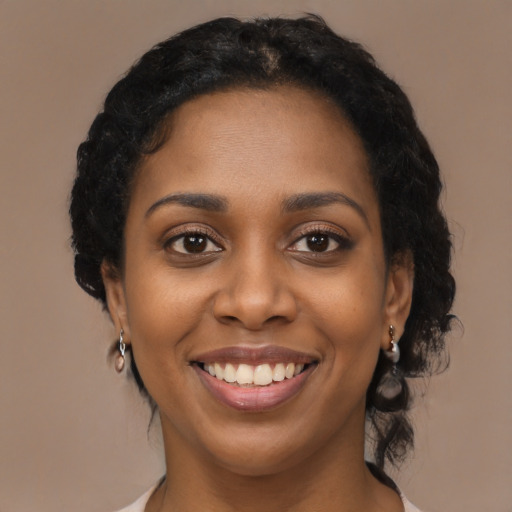 Joyful black young-adult female with long  black hair and brown eyes