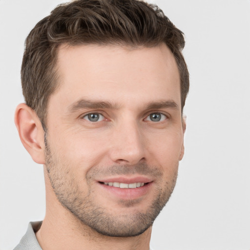 Joyful white young-adult male with short  brown hair and grey eyes