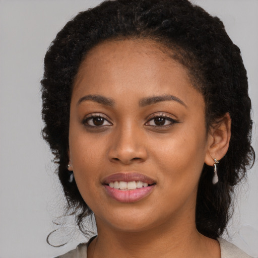 Joyful black young-adult female with long  brown hair and brown eyes