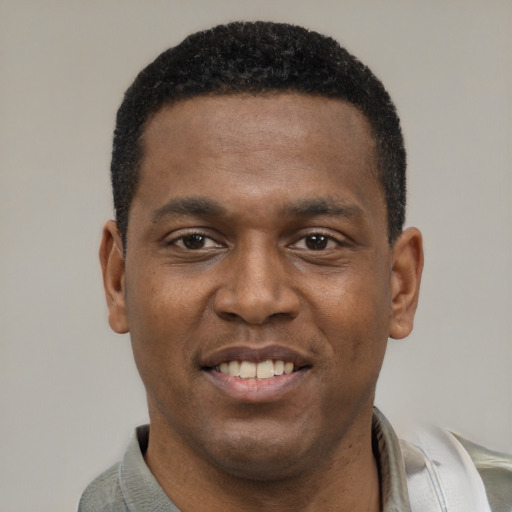 Joyful black young-adult male with short  black hair and brown eyes