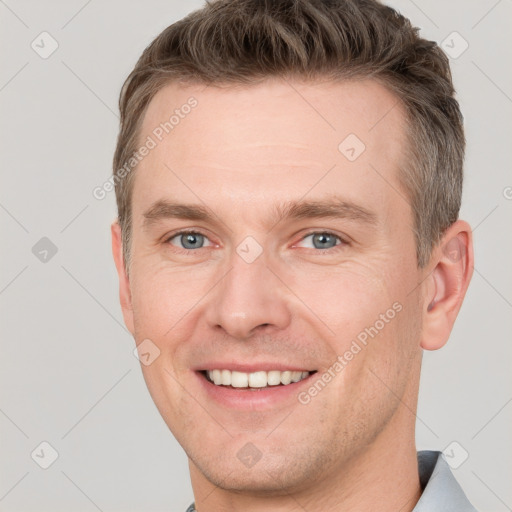 Joyful white young-adult male with short  brown hair and grey eyes