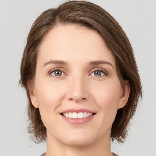 Joyful white young-adult female with medium  brown hair and grey eyes