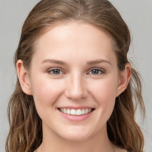 Joyful white young-adult female with long  brown hair and grey eyes