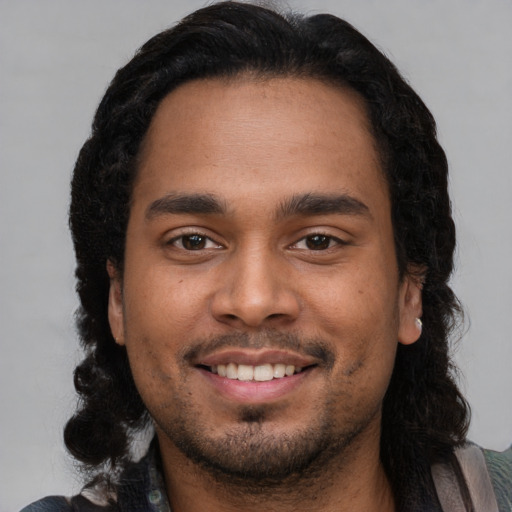 Joyful latino young-adult male with long  black hair and brown eyes