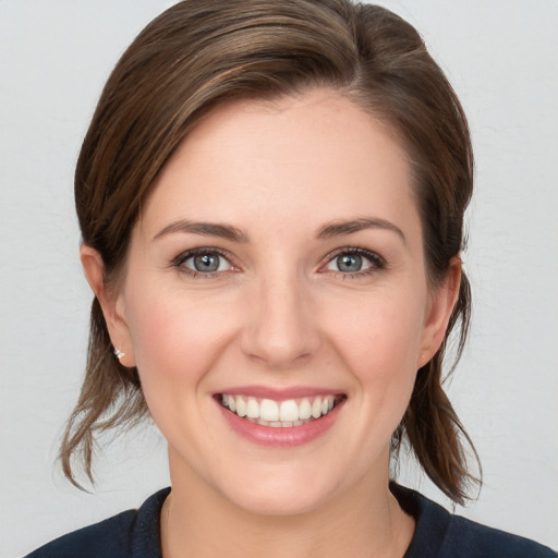 Joyful white young-adult female with medium  brown hair and grey eyes