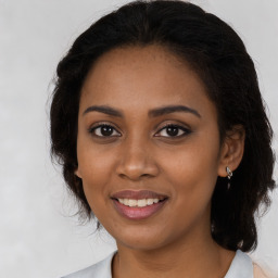 Joyful black young-adult female with long  brown hair and brown eyes