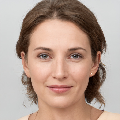 Joyful white young-adult female with medium  brown hair and grey eyes