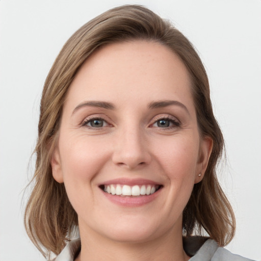 Joyful white young-adult female with medium  brown hair and grey eyes