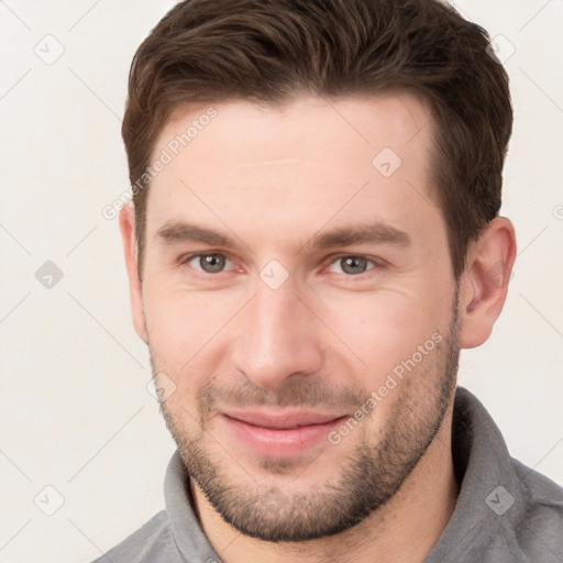 Joyful white young-adult male with short  brown hair and grey eyes