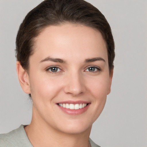 Joyful white young-adult female with short  brown hair and grey eyes