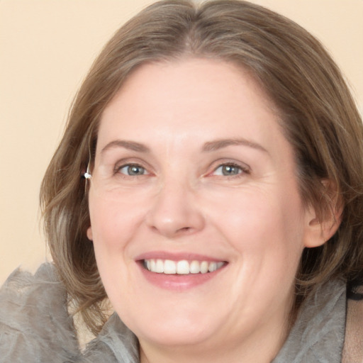 Joyful white adult female with medium  brown hair and blue eyes