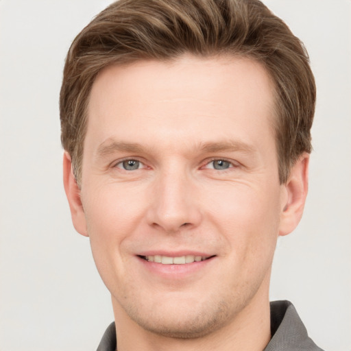 Joyful white young-adult male with short  brown hair and grey eyes