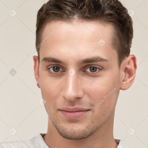 Joyful white young-adult male with short  brown hair and grey eyes