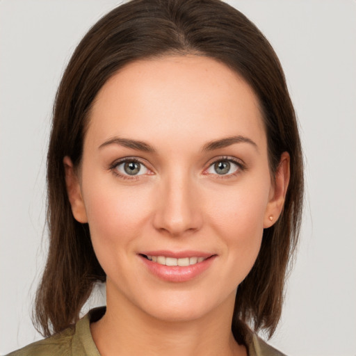 Joyful white young-adult female with medium  brown hair and grey eyes