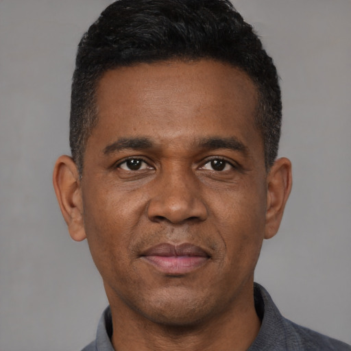 Joyful black adult male with short  black hair and brown eyes