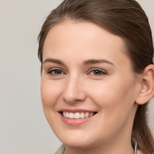 Joyful white young-adult female with medium  brown hair and grey eyes