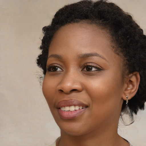 Joyful black young-adult female with long  brown hair and brown eyes