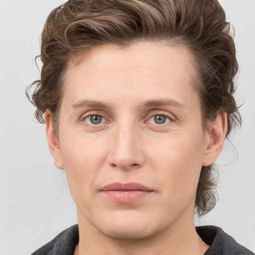 Joyful white young-adult male with medium  brown hair and grey eyes