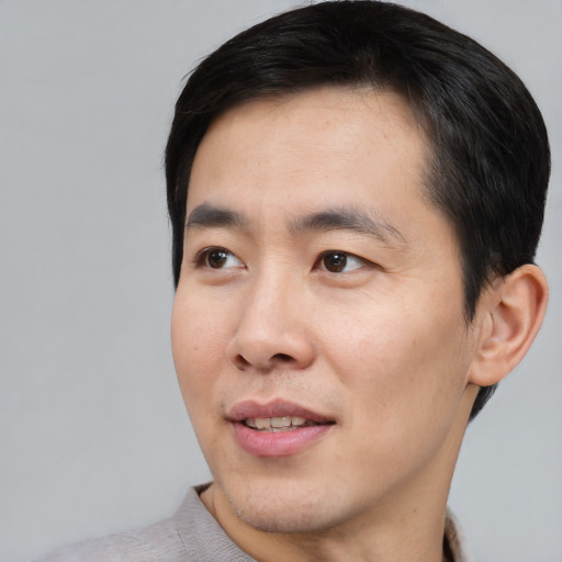 Joyful asian young-adult male with short  black hair and brown eyes