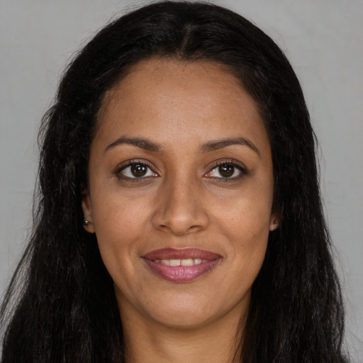 Joyful black young-adult female with long  brown hair and brown eyes