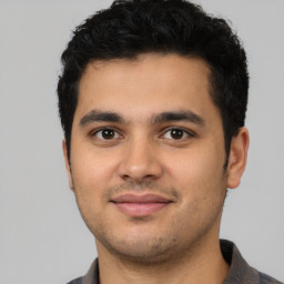 Joyful latino young-adult male with short  black hair and brown eyes