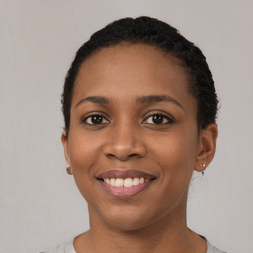 Joyful black young-adult female with short  black hair and brown eyes