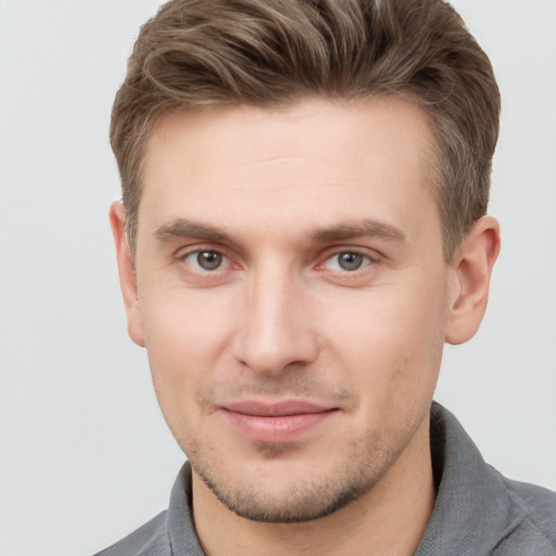 Joyful white young-adult male with short  brown hair and grey eyes