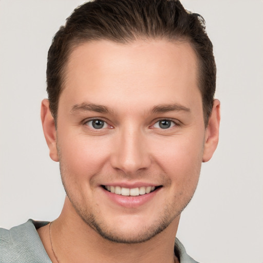 Joyful white young-adult male with short  brown hair and grey eyes