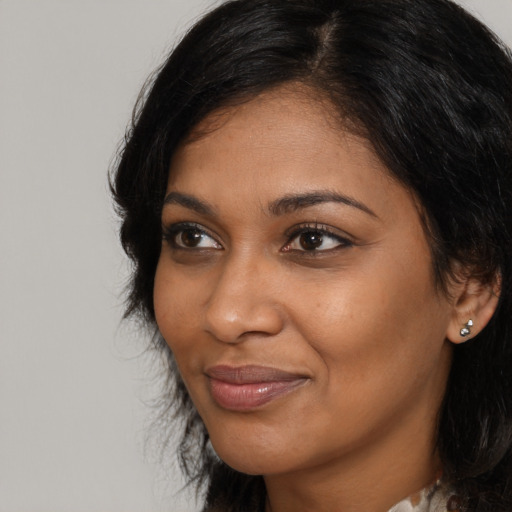 Joyful black young-adult female with long  brown hair and brown eyes