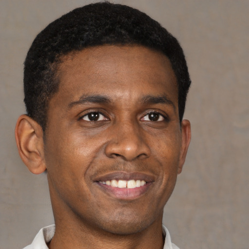 Joyful black young-adult male with short  brown hair and brown eyes