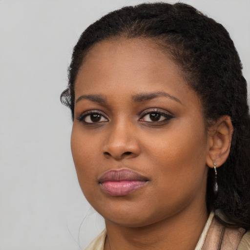 Joyful black young-adult female with long  brown hair and brown eyes