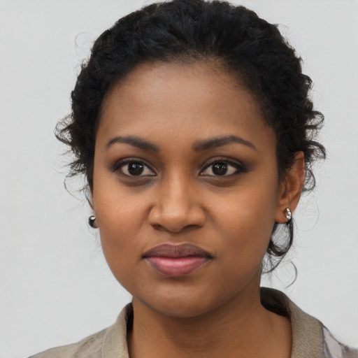 Joyful black young-adult female with long  black hair and brown eyes