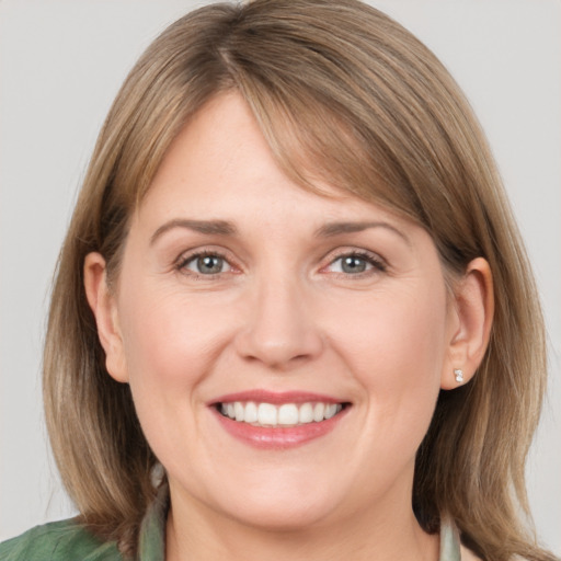 Joyful white young-adult female with medium  brown hair and grey eyes