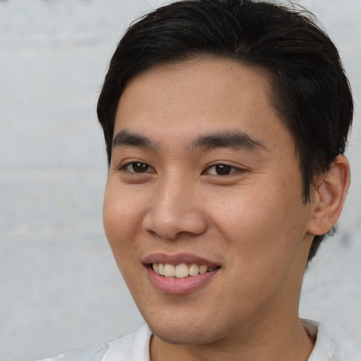 Joyful asian young-adult male with short  brown hair and brown eyes