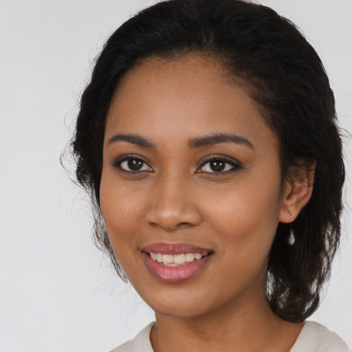 Joyful black young-adult female with long  black hair and brown eyes