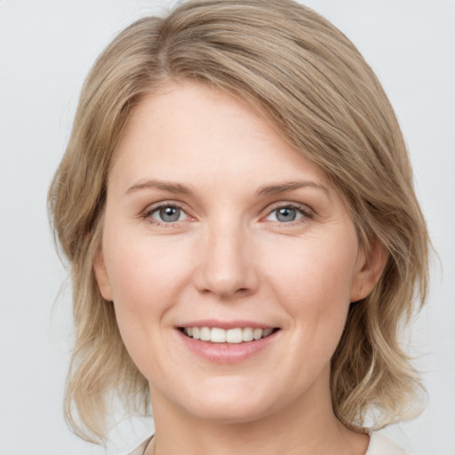 Joyful white young-adult female with medium  brown hair and grey eyes