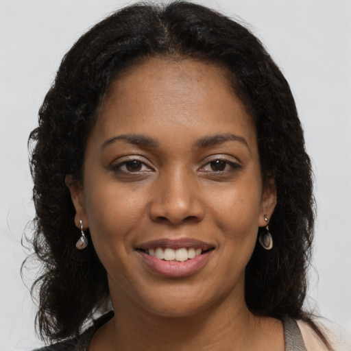 Joyful black young-adult female with long  brown hair and brown eyes