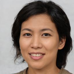 Joyful asian adult female with medium  brown hair and brown eyes