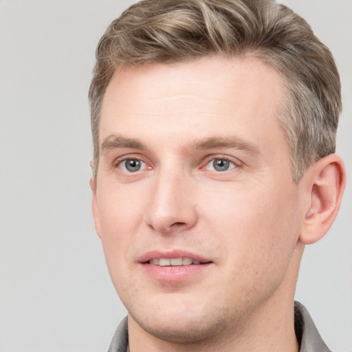 Joyful white young-adult male with short  brown hair and grey eyes