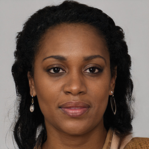 Joyful black adult female with long  brown hair and brown eyes