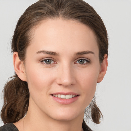 Joyful white young-adult female with medium  brown hair and grey eyes