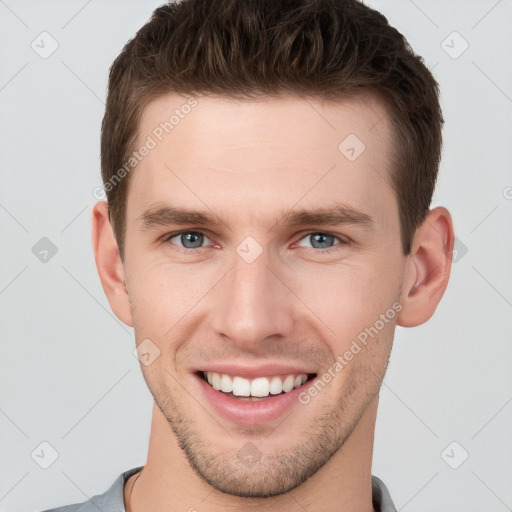 Joyful white young-adult male with short  brown hair and grey eyes