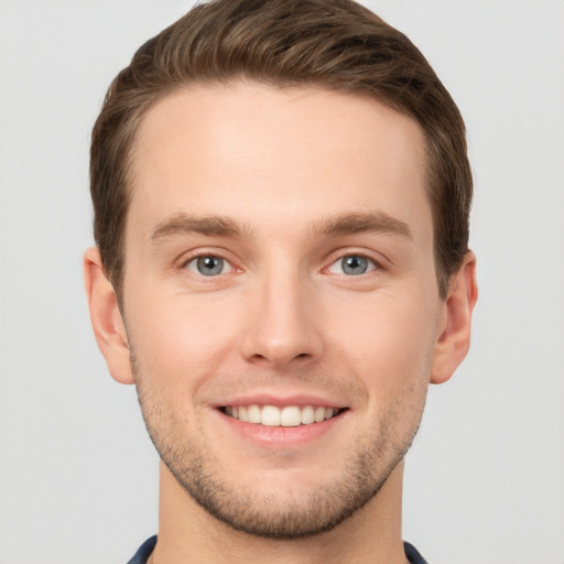 Joyful white young-adult male with short  brown hair and grey eyes