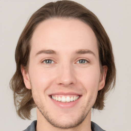 Joyful white young-adult male with medium  brown hair and grey eyes