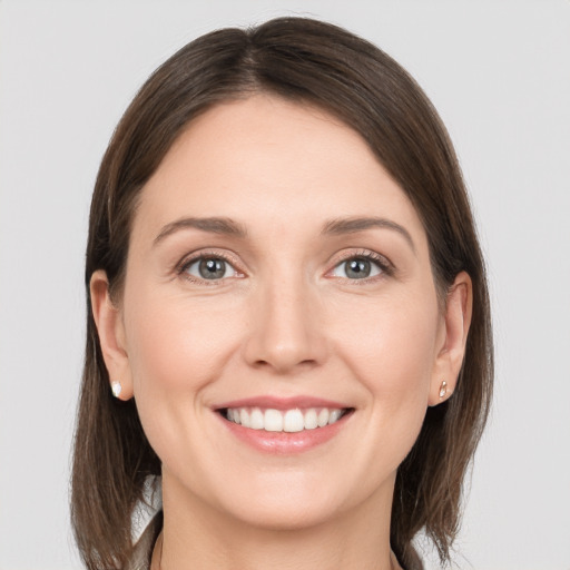 Joyful white young-adult female with medium  brown hair and grey eyes