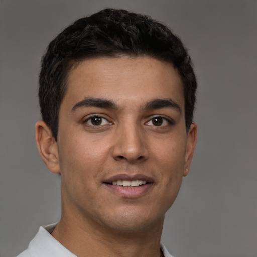 Joyful latino young-adult male with short  brown hair and brown eyes